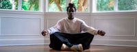 a black man meditating in front of a window