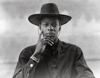 a black man in a hat is posing for a photo